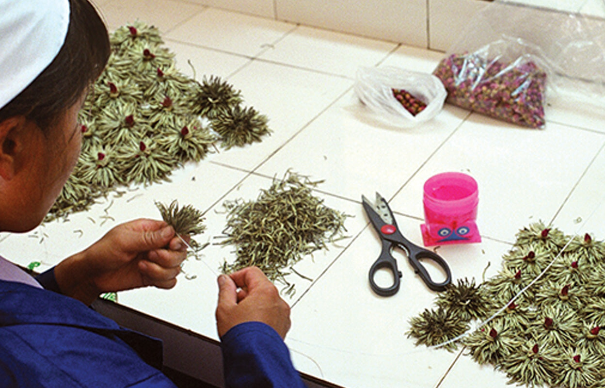 A worker in China hand-sews Numi Flowering Tea blossoms