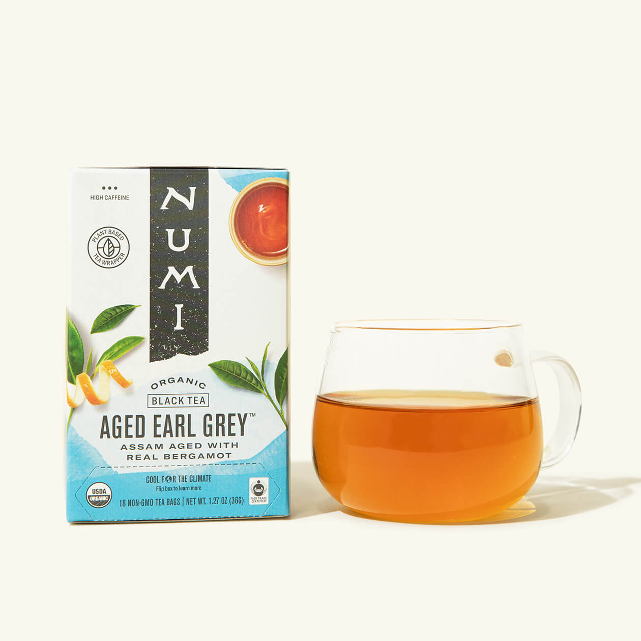 A box of Numi's Aged Earl Grey next to a brewed cup of tea in a clear cup