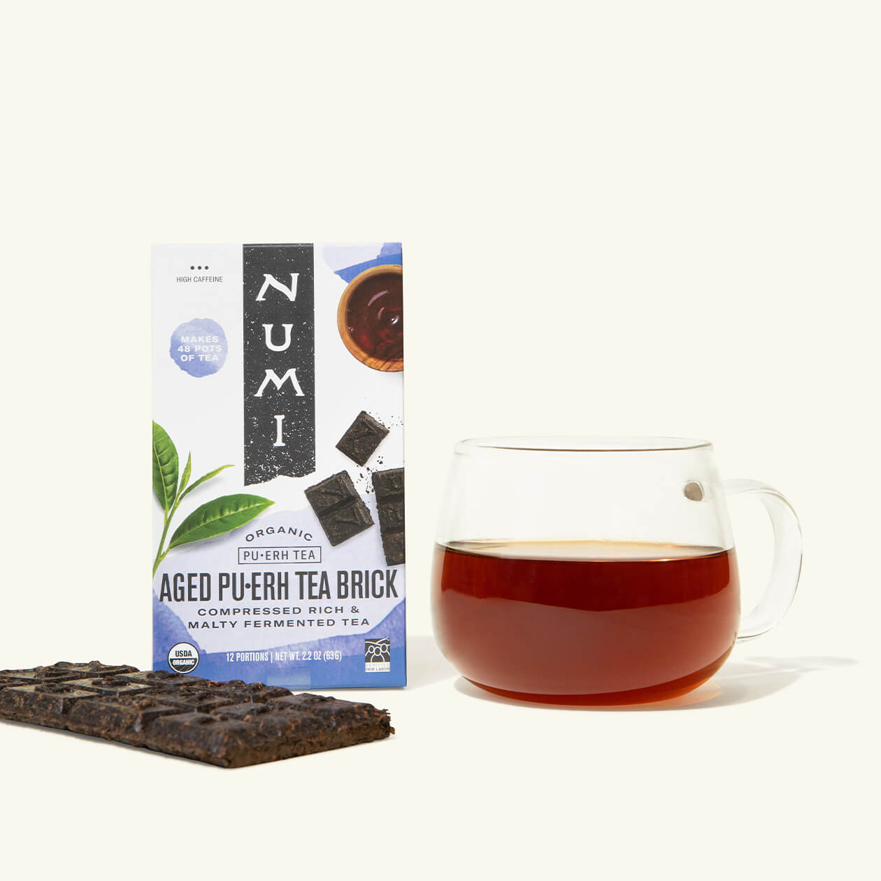 A box of Numi Aged Puerh Tea Brick with a brewed cup of tea