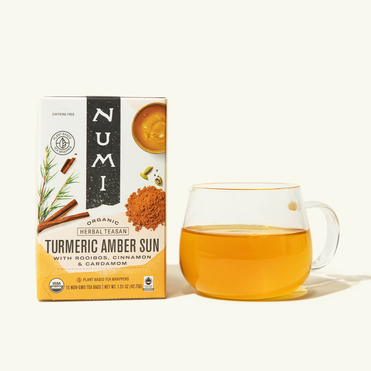A box of Numi's Turmeric Amber Sun next to a brewed cup of tea in a clear cup