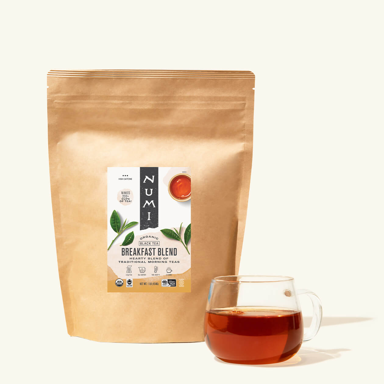 A bag of loose leaf Numi Breakfast Blend tea with a cup of brewed tea in a clear cup