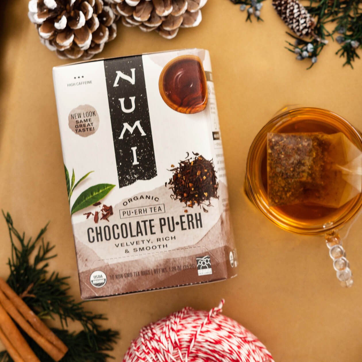 A box of organic Numi Chocolate Puerh with a cup of brewed tea on a gold tray