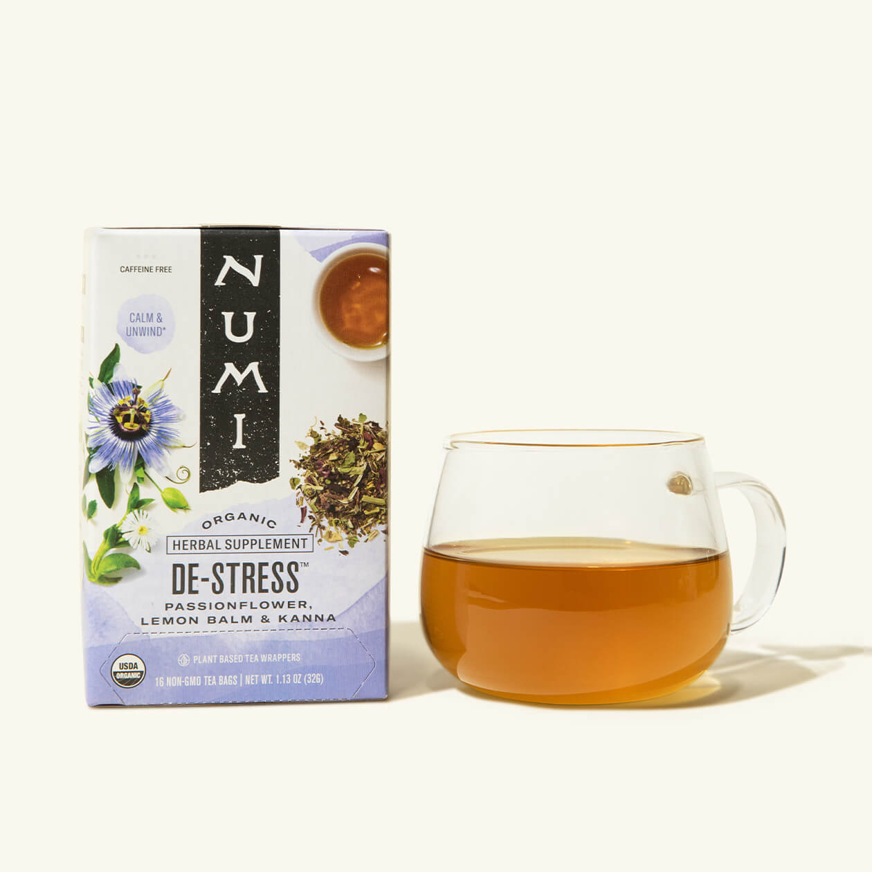 A box of Numi's De-Stress tea next to a brewed cup of tea in a clear cup