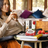 A woman sitting in her living room enjoying a cup of hot Golden Chai tea with strawberries