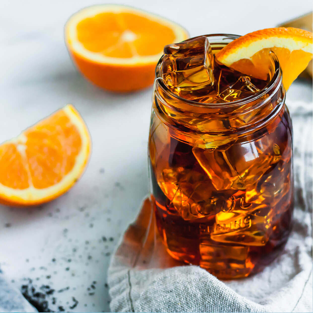 A jar of black iced tea garnished with fresh oranges