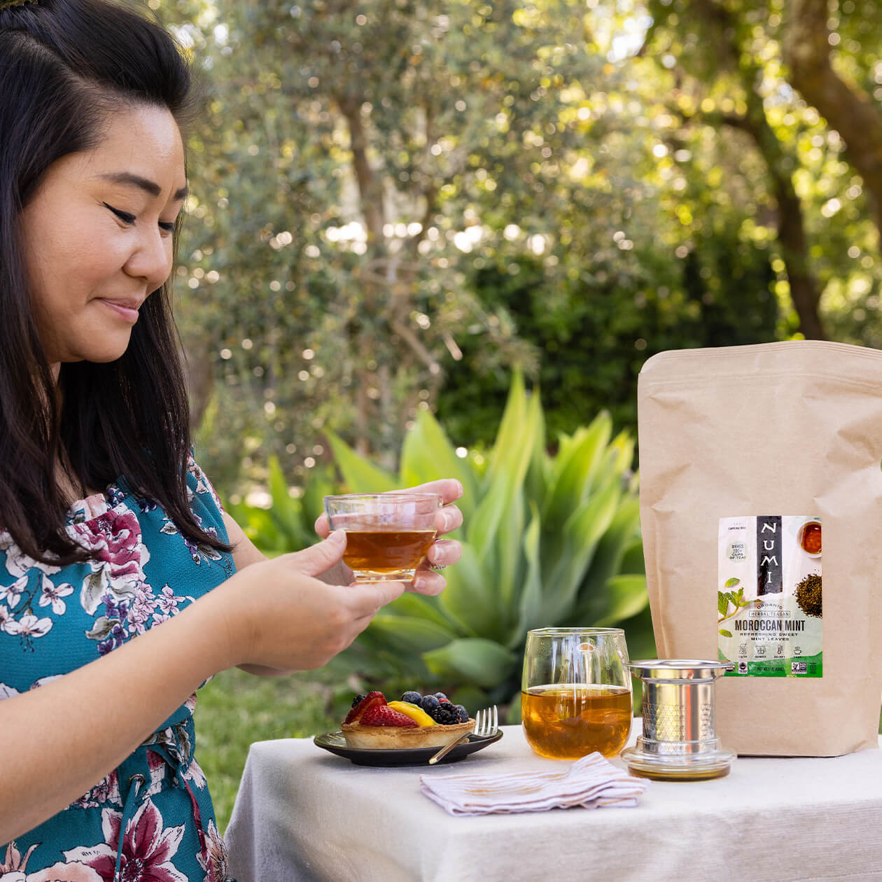 A woman enjoys a cup of loose leaf Moroccan Mint tea with her dessert outdoors