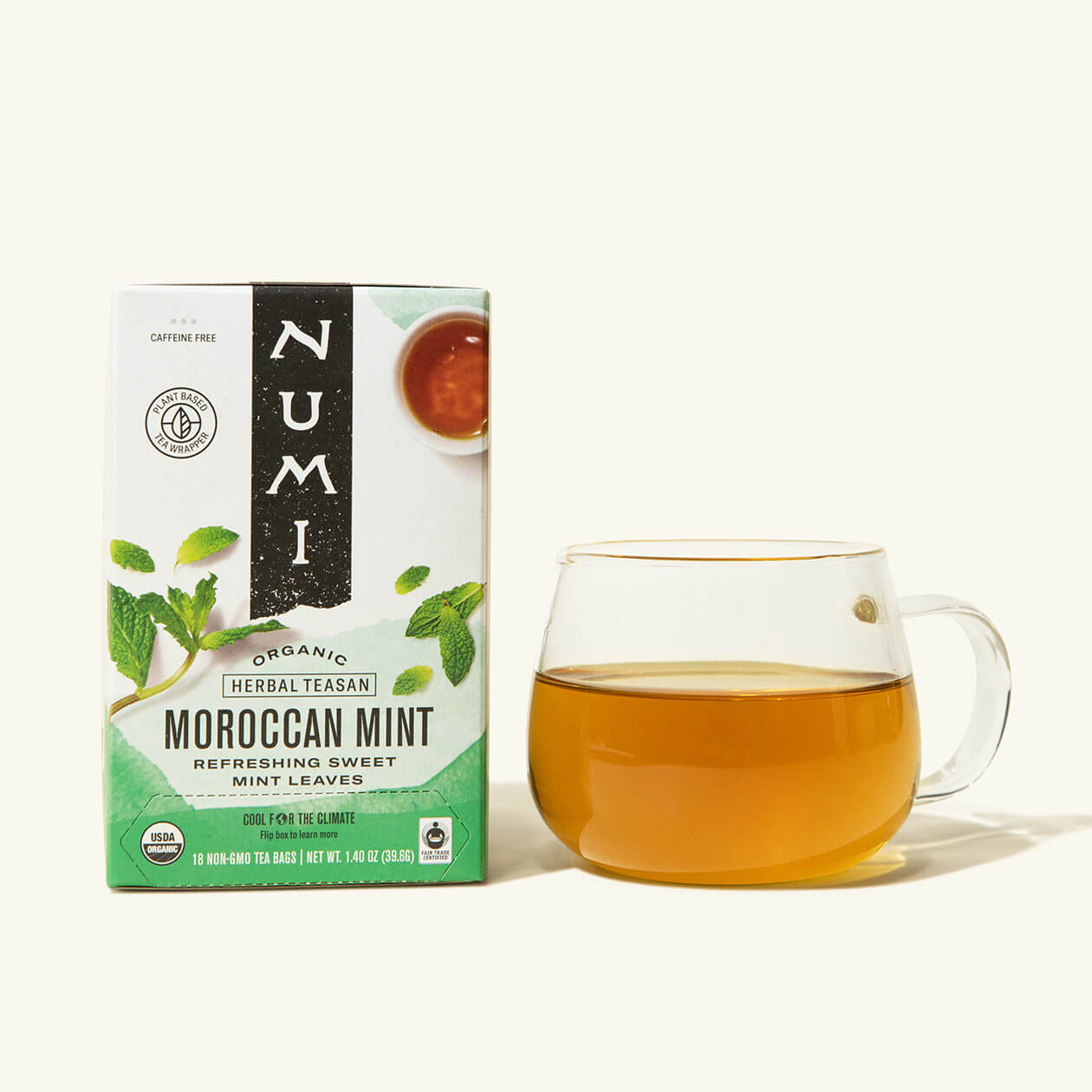 A box of Numi's Moroccan Mint tea next to a brewed cup of tea in a clear cup
