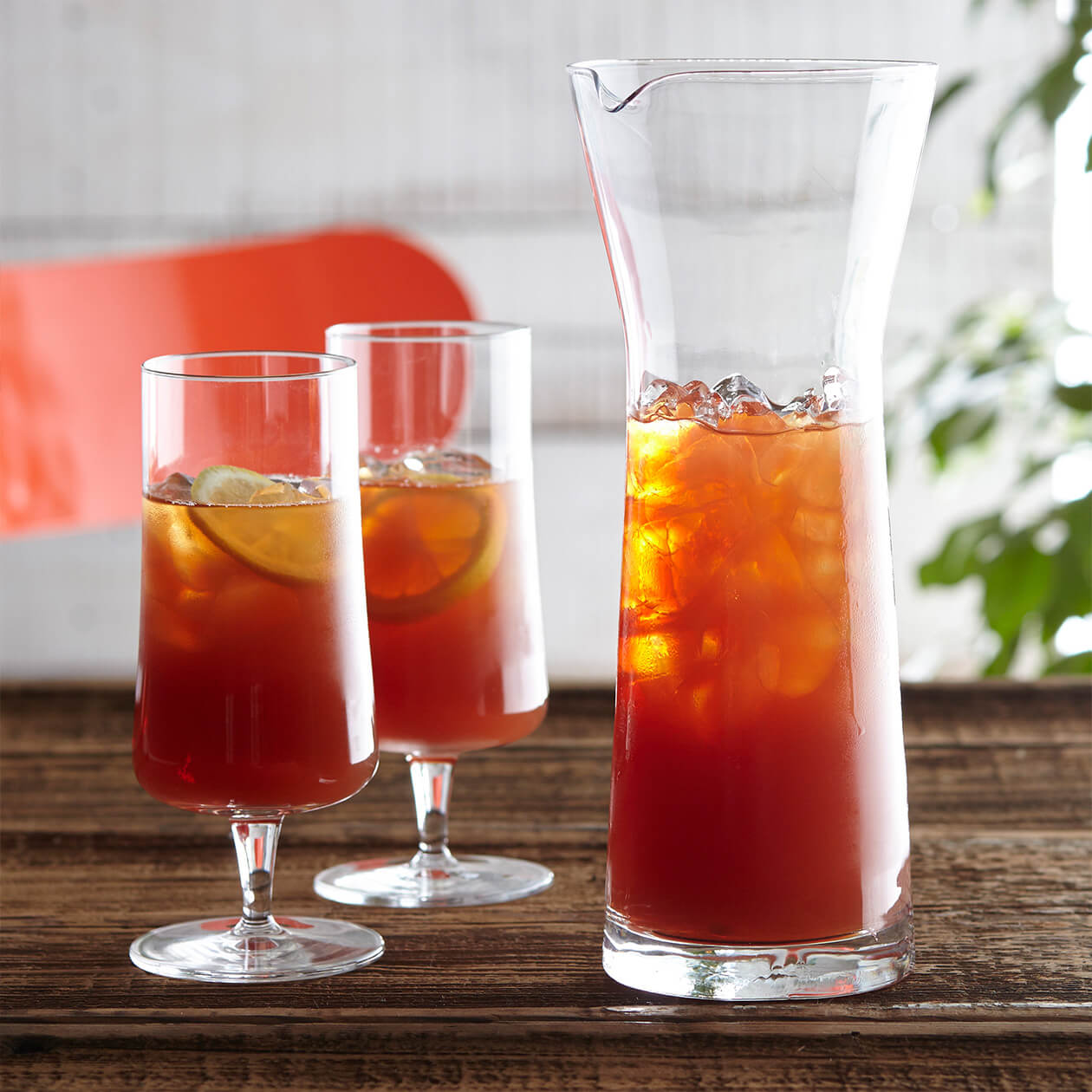 A pitcher of High Mountain Black iced tea served in two glasses with lemon in a cafe setting