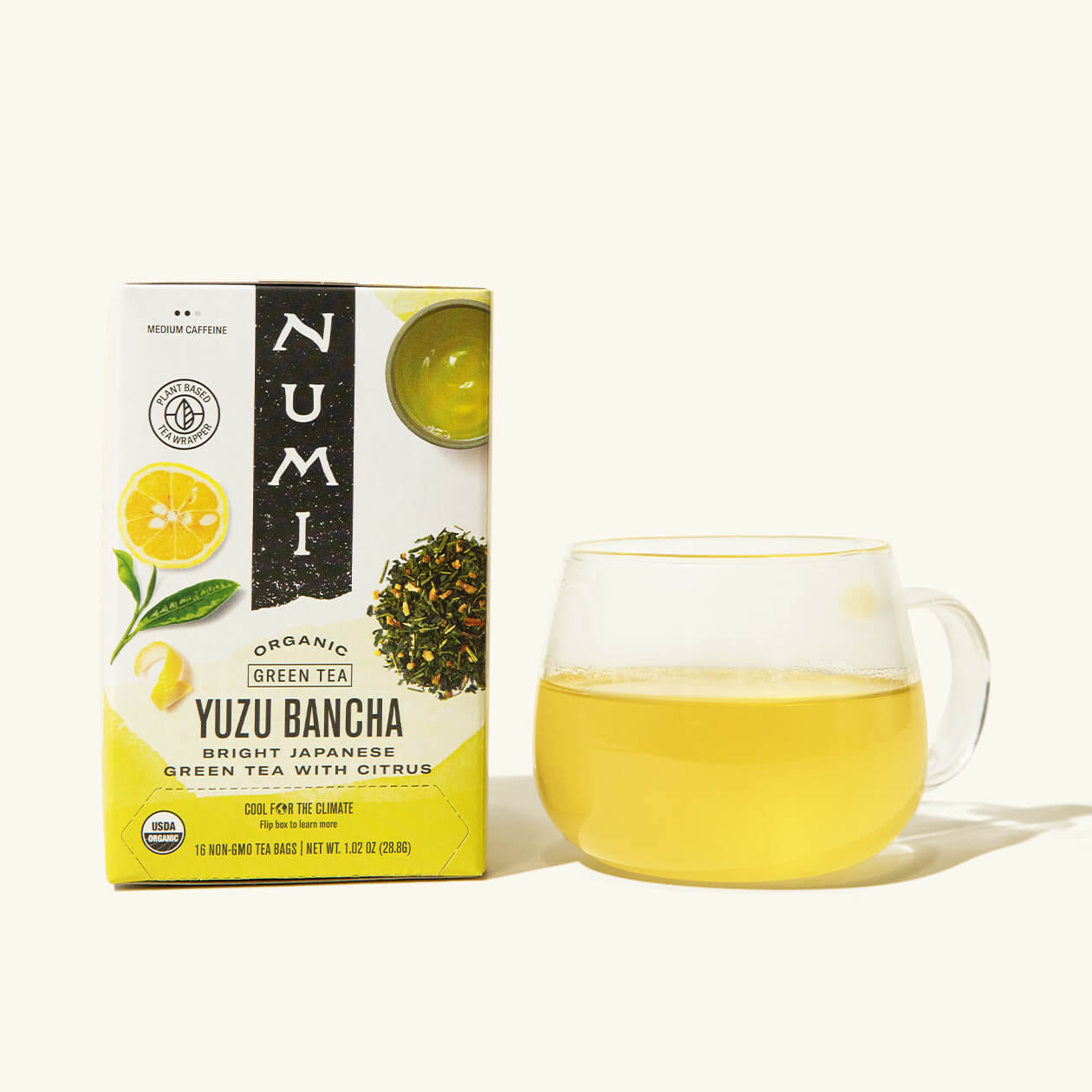 A box of Numi Yuzu Bancha next to a brewed cup of tea in a clear cup