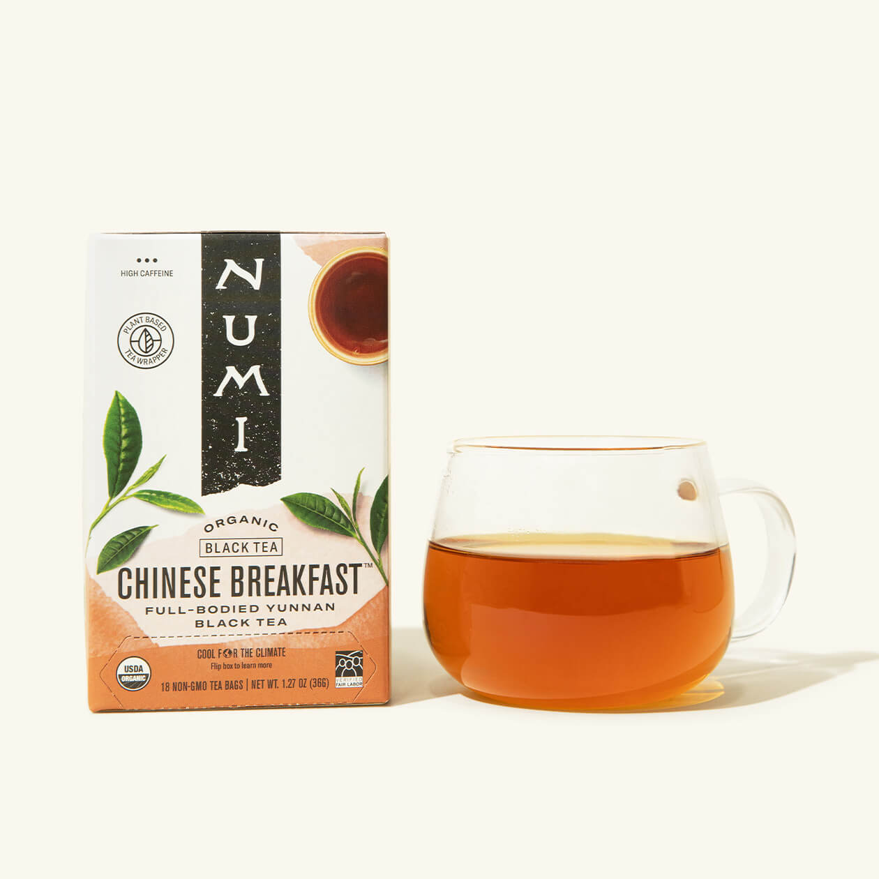 A box of Numi's Chinese Breakfast next to a brewed cup of tea in a clear cup
