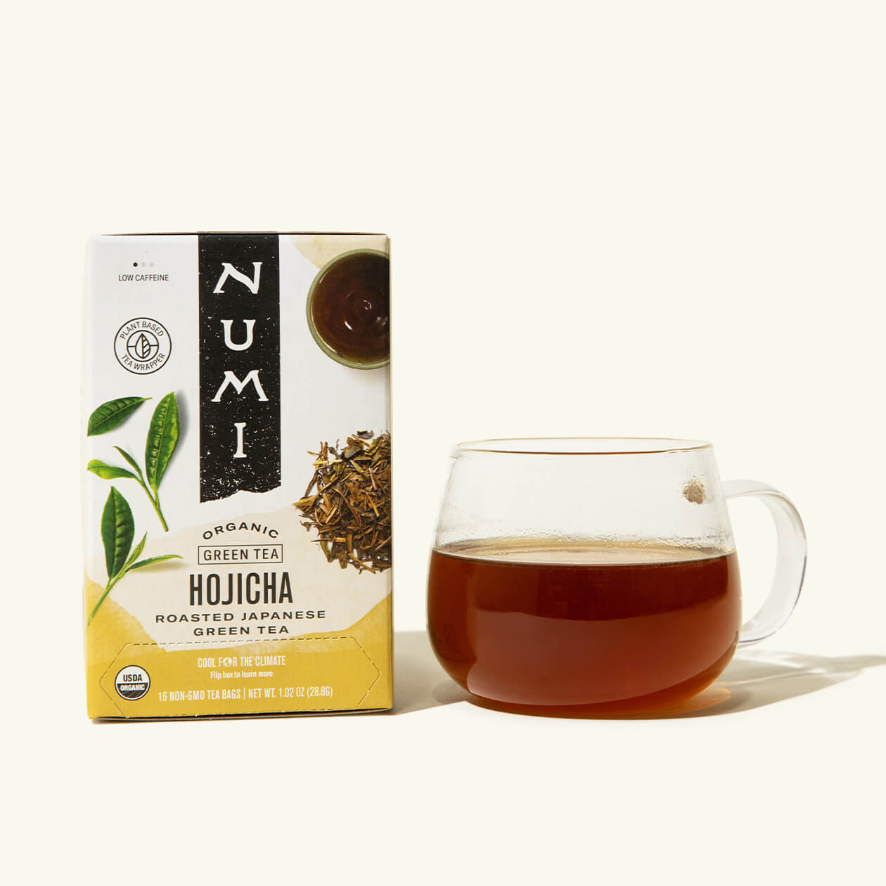 A box of Numi's Hojicha next to a brewed cup of tea in a clear cup