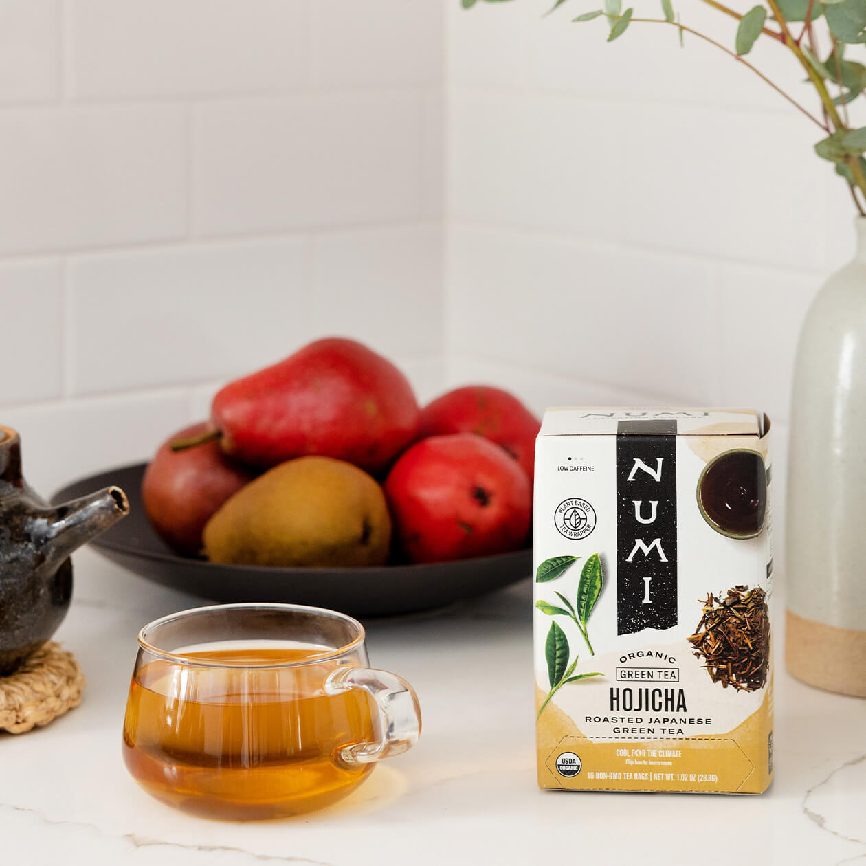 A cup of brewed Hojicha sitting on a kitchen counter with the Hojicha box