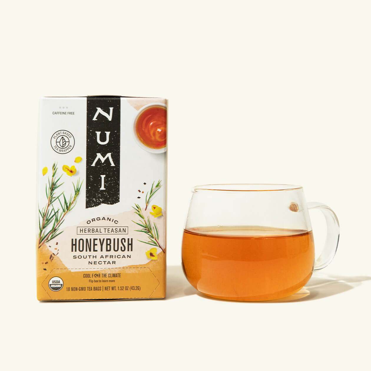 A box of Numi's Honeybush next to a brewed cup of tea in a clear cup