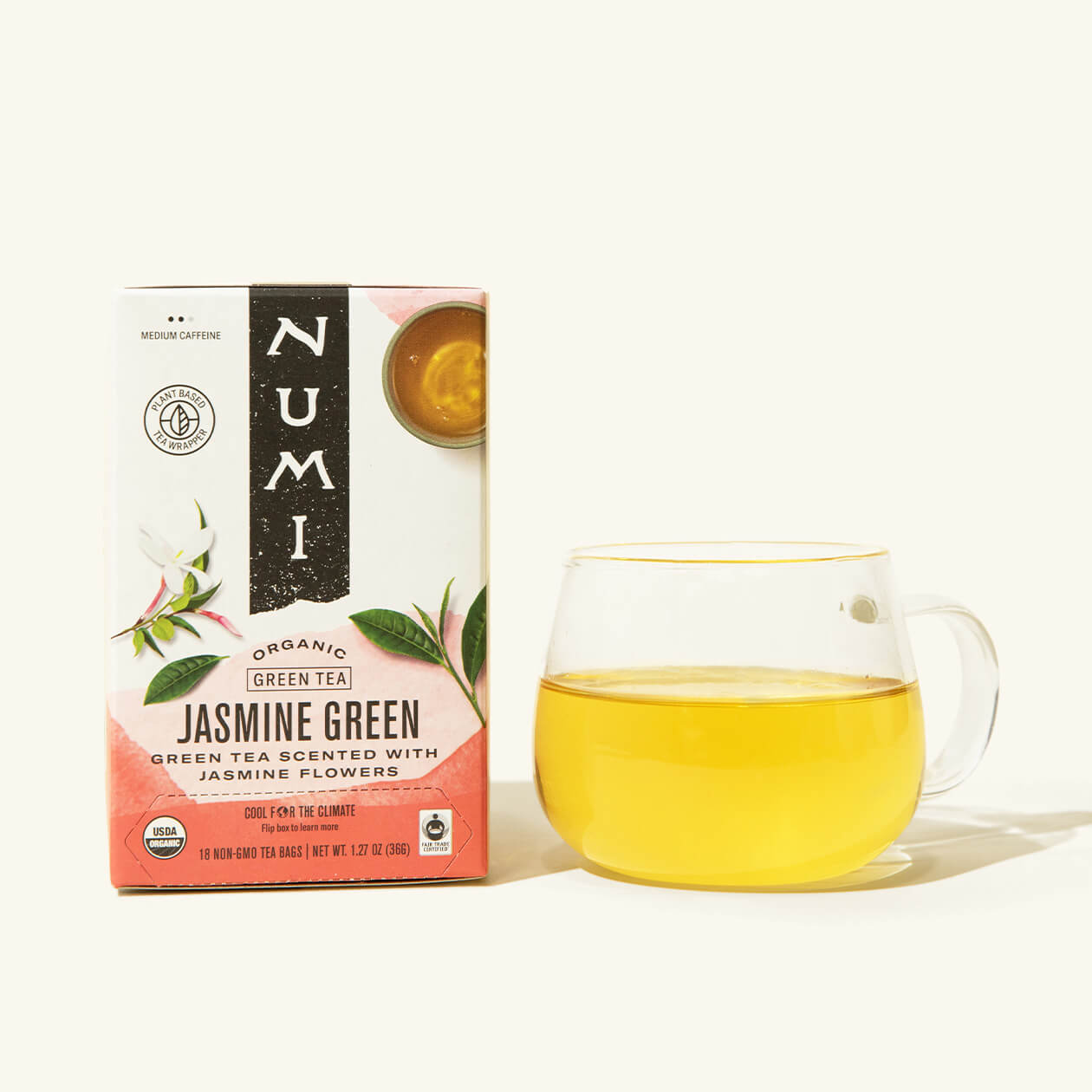 A box of Numi's Jasmine Green next to a brewed cup of tea in a clear cup