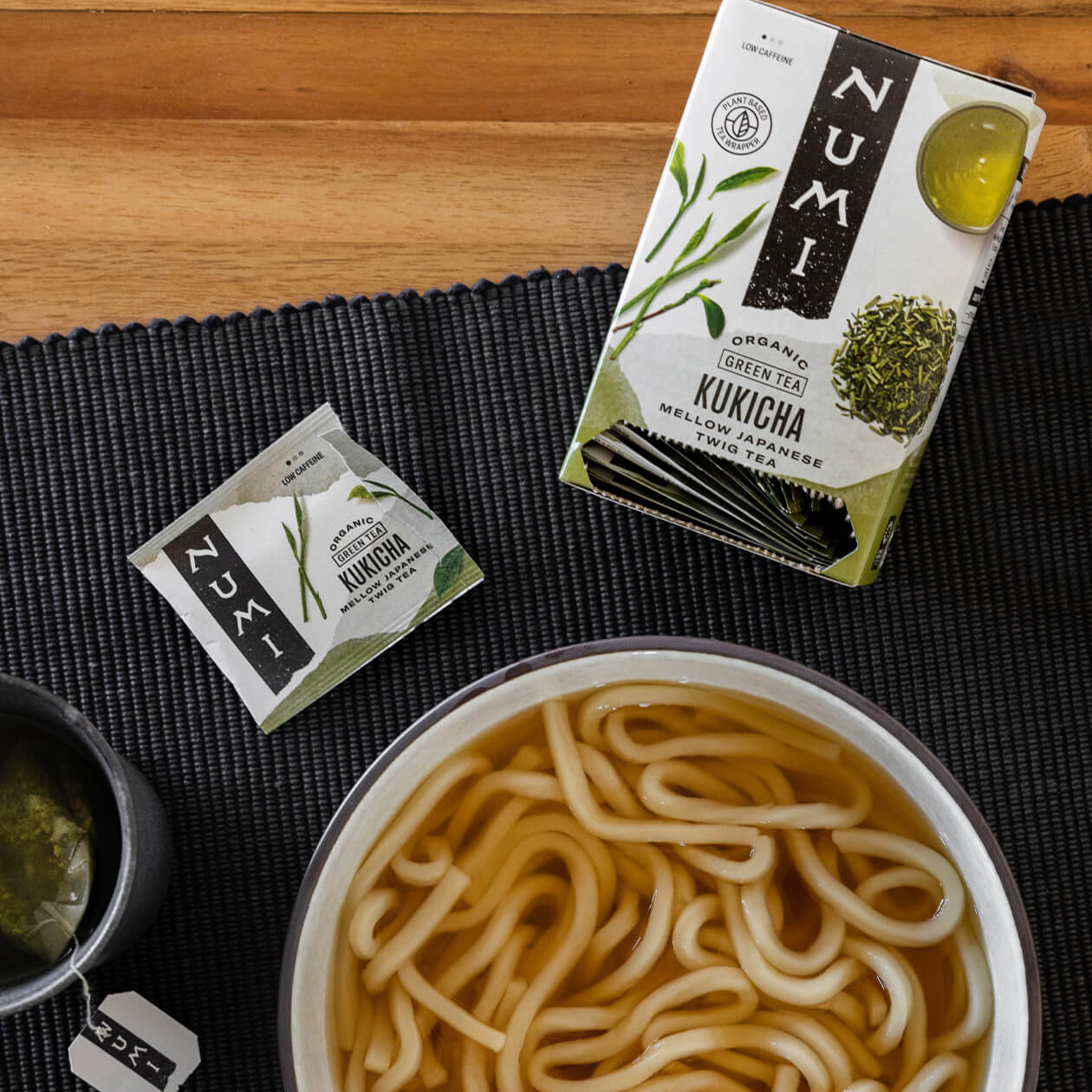 A box of Kukicha tea next to a bowl of noodle soup