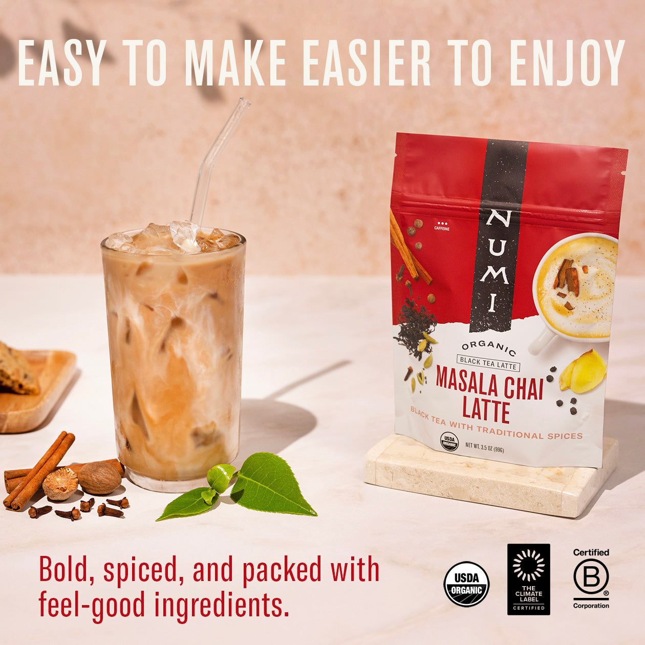 Numi Masala Chai Latte package with iced chai latte and spices on a white surface