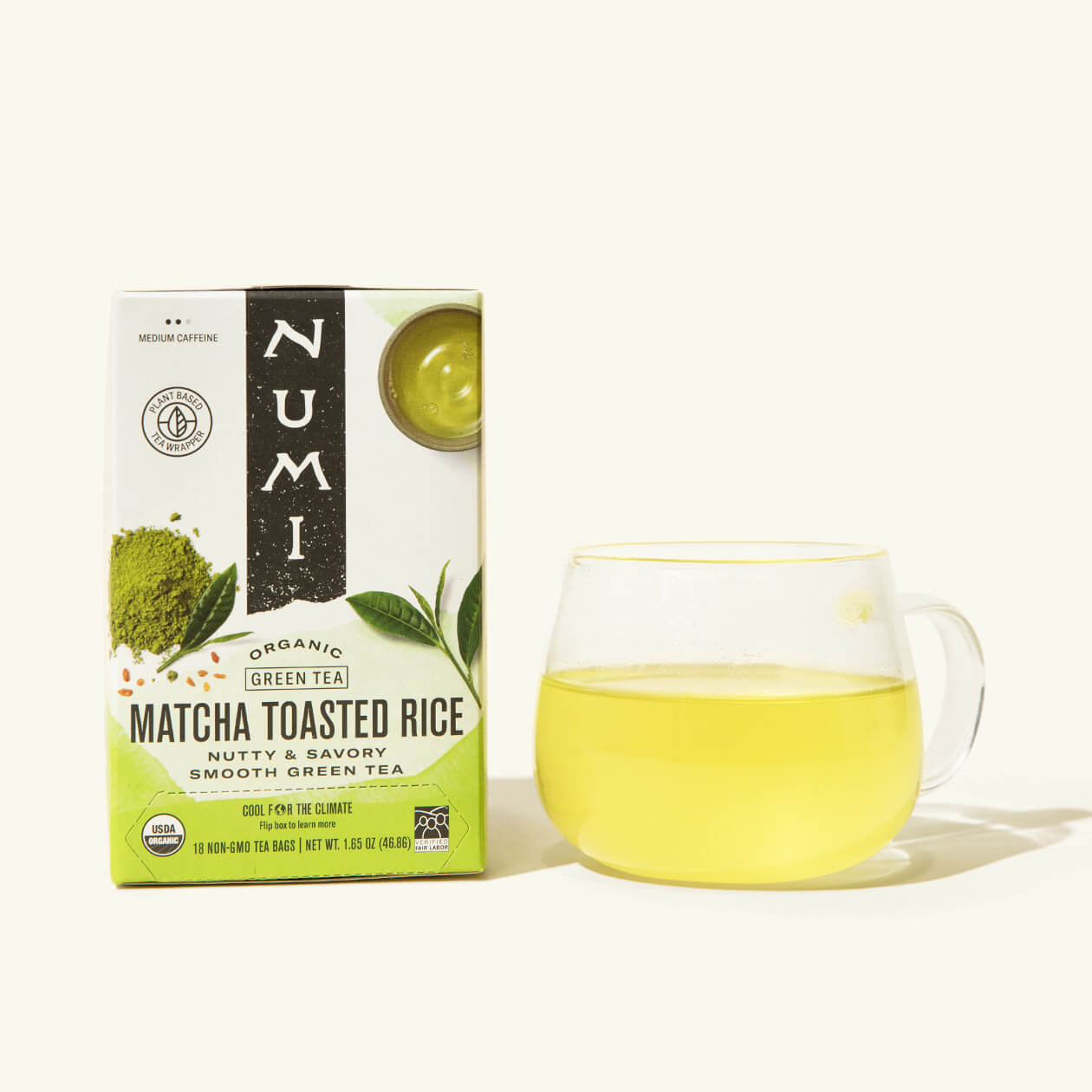 A box of Numi's Matcha Toasted Rice next to a brewed cup of tea in a clear cup