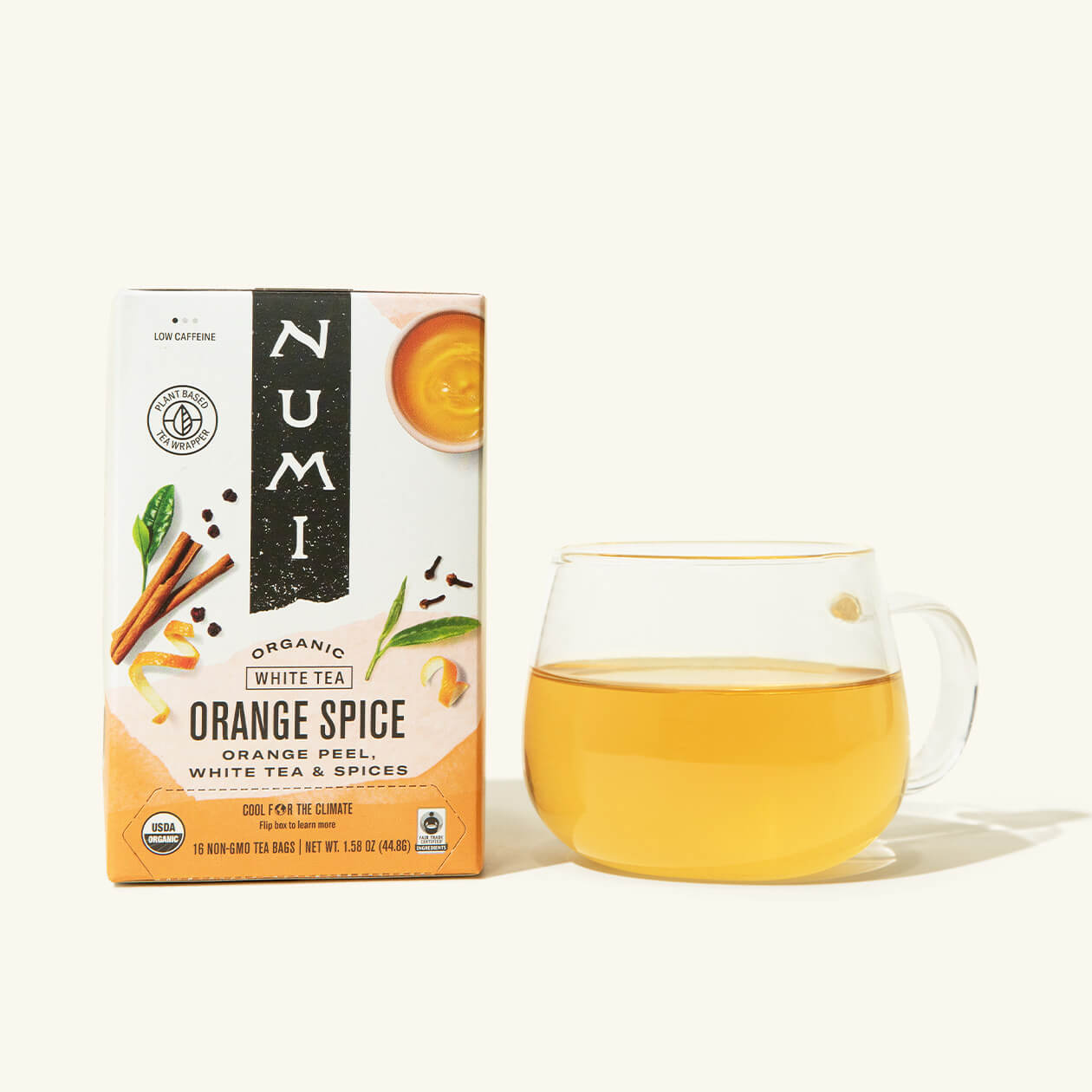 A box of Numi's Orange Spice next to a brewed cup of tea in a clear cup