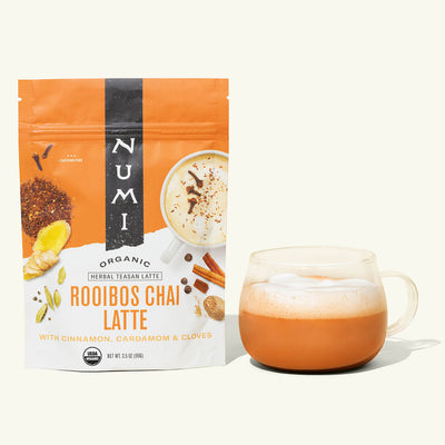 Numi Roobios Chai Latte package with a glass of chai latte on a white background
