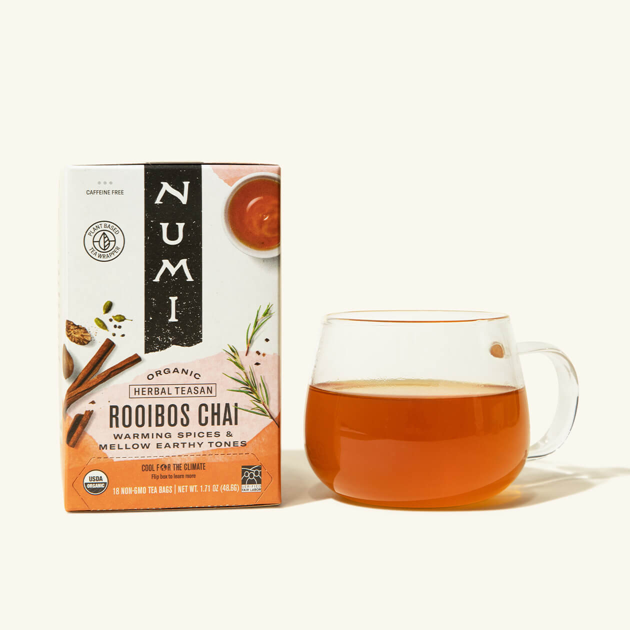 A box of Numi's Rooibos Chai next to a brewed cup of tea in a clear cup
