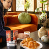 A woman enjoys her breakfast croissant and touch of chili drinking chocolate in her modern living room